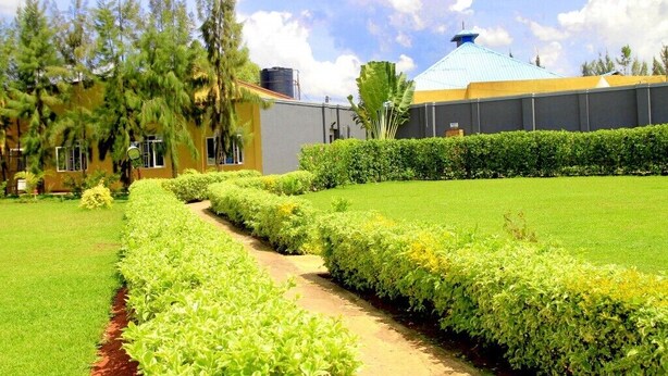 A well-maintained garden with a pathway leading to a building with a blue roof.