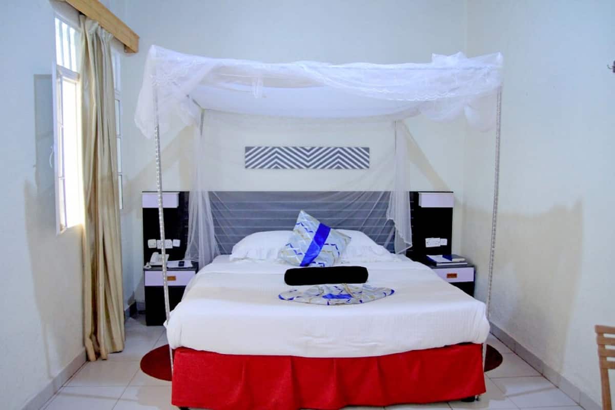 A neatly arranged bedroom with a bed, bedside tables, and a window with curtains.