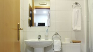 A bathroom with a sink, toilet, and mirror. - CH Murallas II (Madrid)