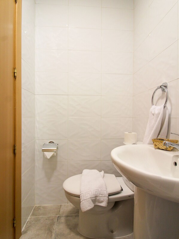 A bathroom with a toilet, a sink, and a towel rack.