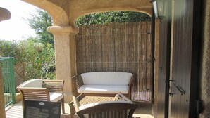 Ein möblierter Patio mit Holzbank, gepolstertem Sofa und Grill.