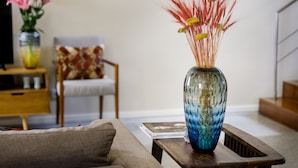 Una sala de estar con un sofá, una mesa de centro y un jarrón decorativo con flores.