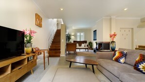 Una sala moderna con un televisor de pantalla plana, un sofá, una mesa de centro y una escalera que lleva a otra habitación.