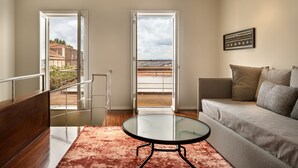 Una sala de estar moderna con una mesa de vidrio, un sofá y vistas a un balcón con barandilla.