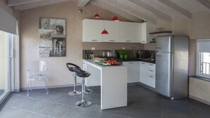 Een moderne keuken met witte kastjes, een roestvrijstalen koelkast en een bar met twee krukken.