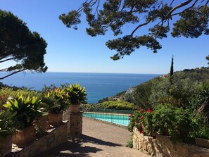 Una escalera de piedra que lleva a una piscina con vista al mar y al paisaje costero.