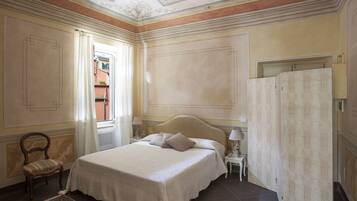 Una camera da letto con un letto grande, una sedia, un comodino e una porta con tenda.