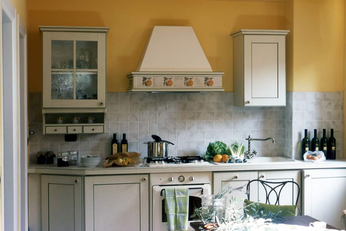 Una cocina con estufa, lavaplatos, armarios y salpicadero de azulejos.