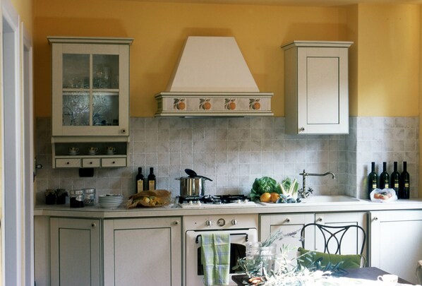 Une cuisine équipée d’une cuisinière, d’un évier, de placards et d’un pare-feu en carreaux.