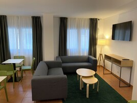 Una sala de estar moderna con un sofá, dos sillones, una mesita, un televisor y una lámpara.