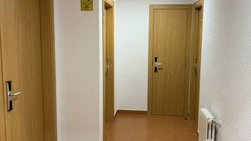 A hallway with wooden doors, a tiled floor, and a ceiling light.
