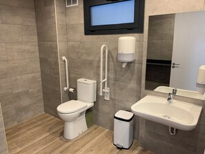 A modern bathroom with a toilet, bidet, sink, and trash bin. - Musher (Pas de la Casa)