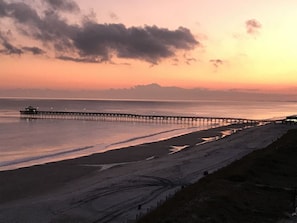 Un muelle que se adentra en aguas tranquilas al atardecer.