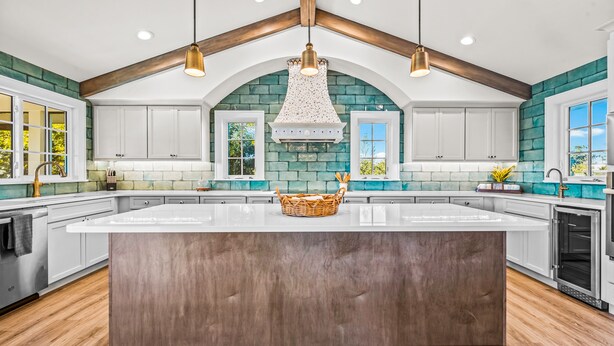A spacious kitchen with a large island, white cabinets, teal accent walls, and a farmhouse-style ceiling. - Luxury Home with Pool and Dock for Fishing! (Anna Maria)