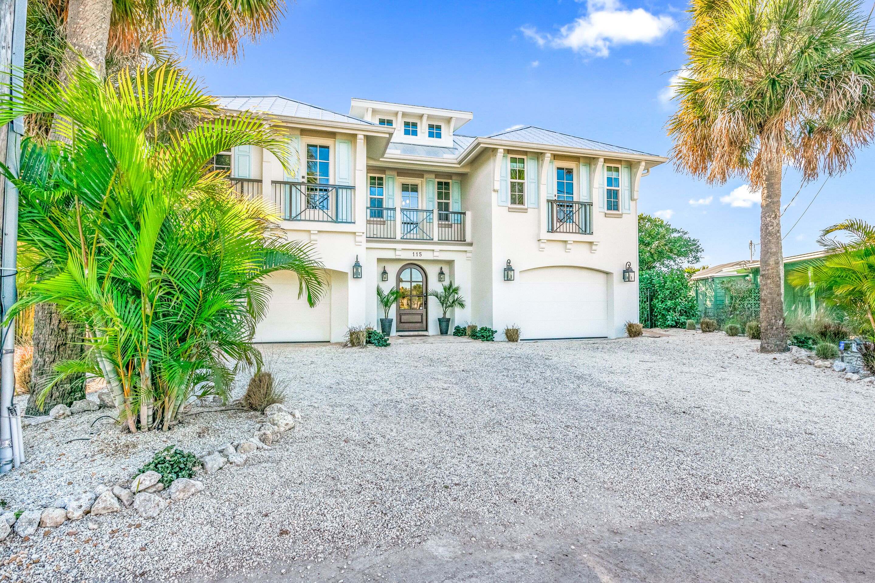 A two-story house with a gravel driveway, a front door, and a number '115' above it.