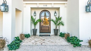 A building with a number 115, a brown door with glass panels, and two potted plants on either side. - Luxury Home with Pool and Dock for Fishing! (Anna Maria)