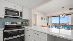 Uma cozinha moderna com eletrodomésticos de aço inoxidável, uma ilha grande e vista para a cidade através de amplas janelas.