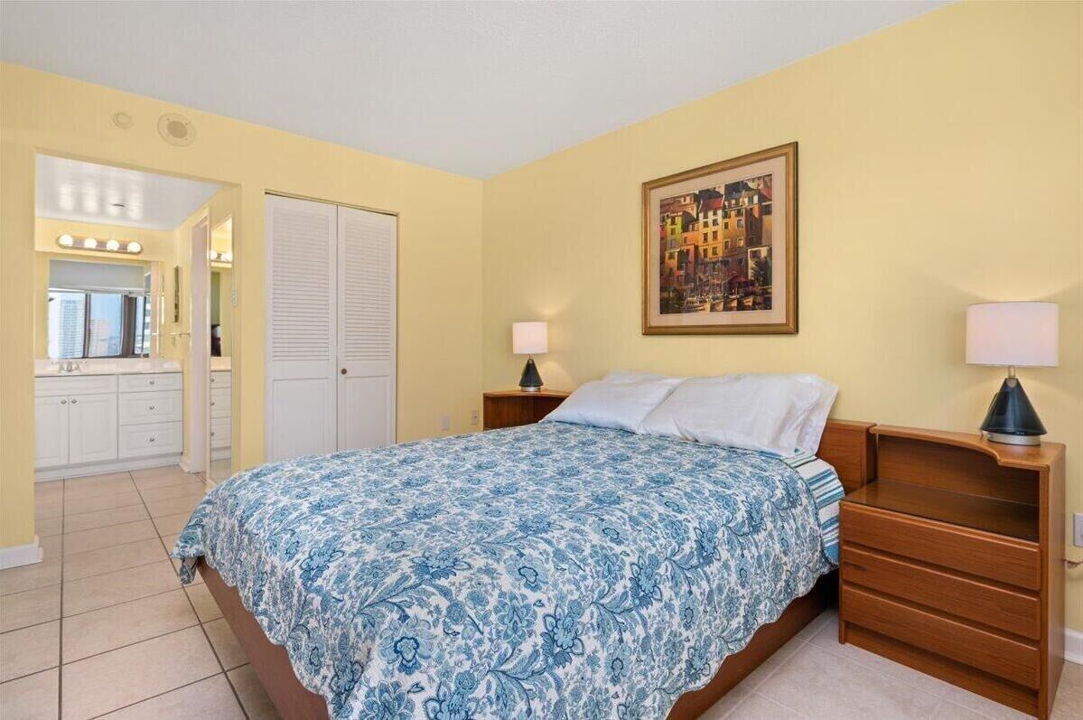 Une chambre à coucher avec un lit, des tables de chevet, un miroir et une porte.