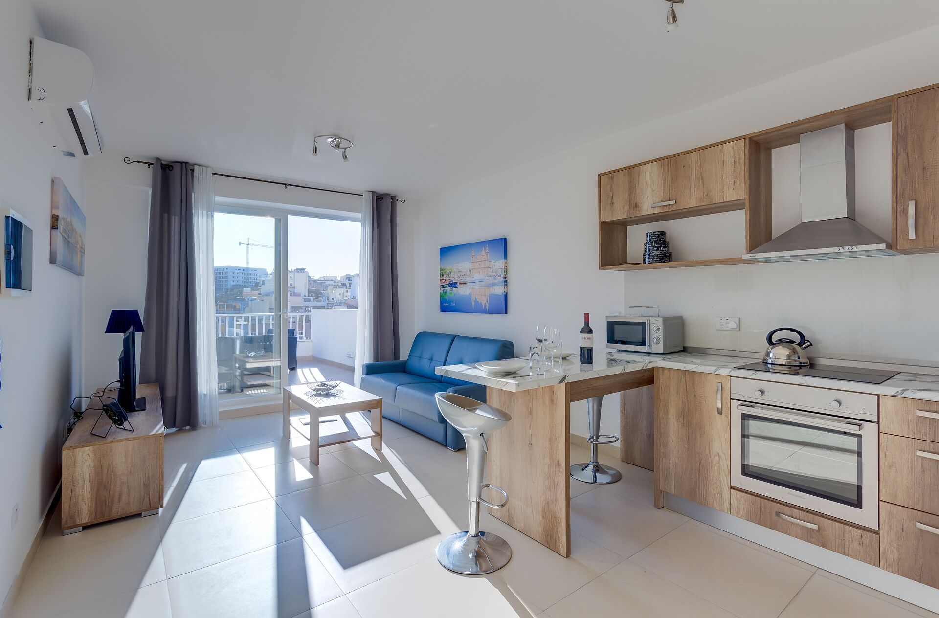 A modern apartment with a balcony, a kitchen with wooden cabinets, a dining area, and a living room with a blue sofa.