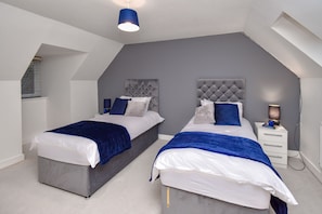 A modern bedroom with two beds, a nightstand, and a ceiling light. - Foxley Place - MK City house (Milton Keynes)