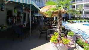 A hotel with outdoor seating, a pool, and a palm tree.