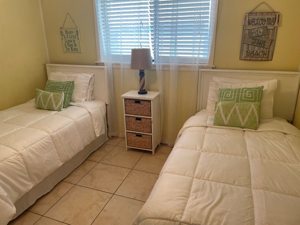 Een slaapkamer met twee bedden, een nachtkastje met een lamp en wanddecoraties.