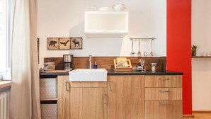 Une cuisine moderne avec des meubles en bois, un évier blanc et un mur d’accent rouge.