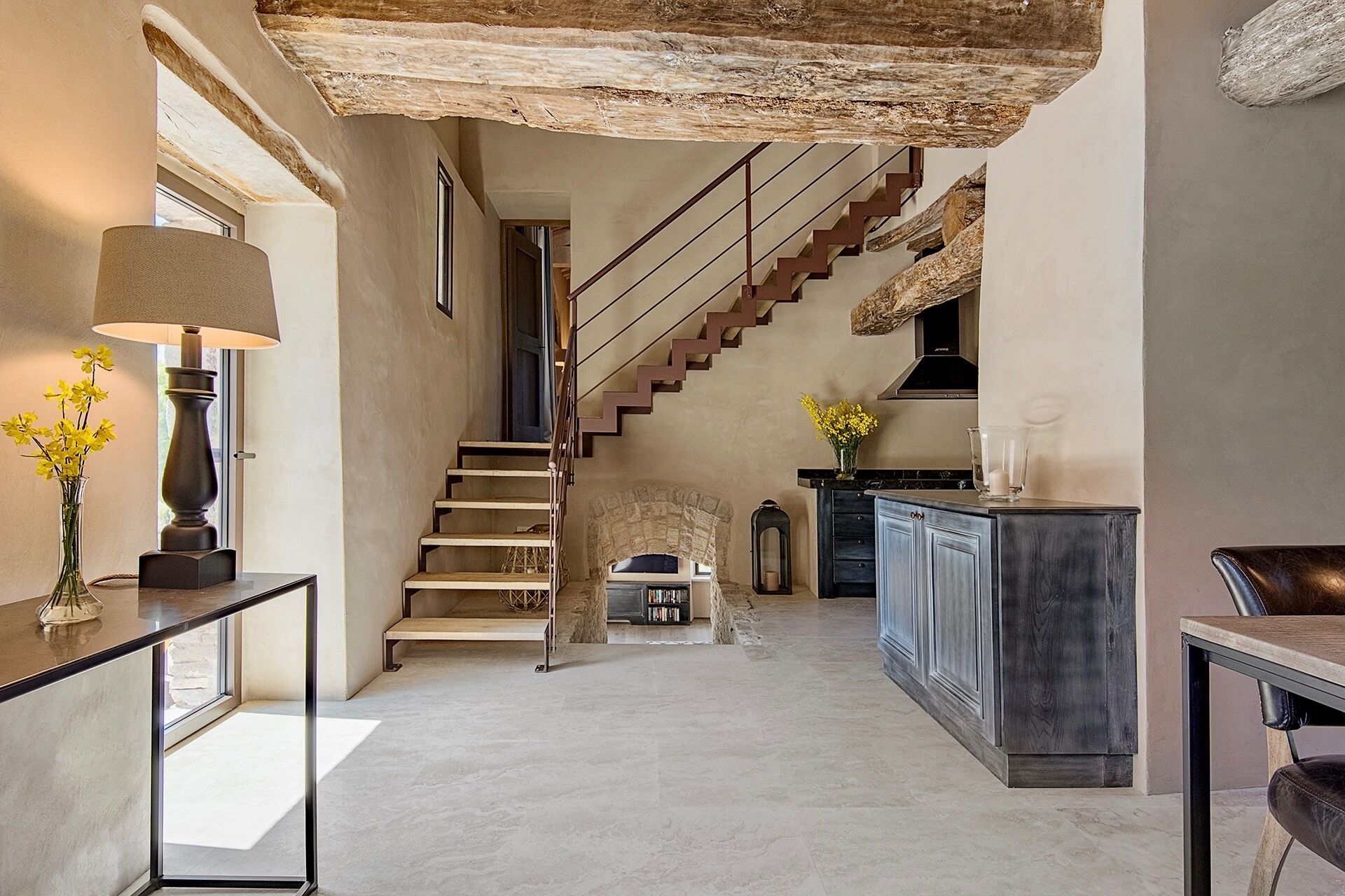 Un hall d’entrée spacieux avec un escalier menant à un deuxième étage, un coin cuisine avec un bar, et un espace détente avec une table et des chaises.