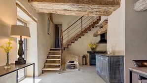 A spacious hallway with a staircase leading to a second floor, a kitchen area with a bar, and a seating area with a table and chairs.