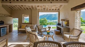 A spacious patio with wicker furniture, a small table with fruit, and a view of mountains.