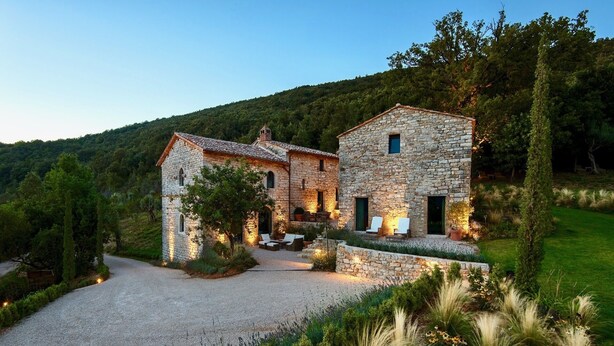 A stone house with a gravel driveway and a well-maintained garden.
