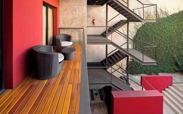 Un espace extérieur moderne doté d’une terrasse en bois, d’un escalier et d’un mur rouge.
