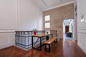 A hallway with a wooden bench, a railing, and a potted plant.