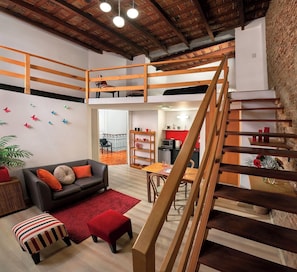 A loft-style living space with a wooden staircase, a dining area, and a kitchen visible through an open door. - Mariposita De San Telmo (Buenos Aires)