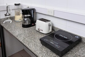 Un plan de travail de cuisine avec une machine à café, un grille-pain et une plaque de cuisson à induction noire.
