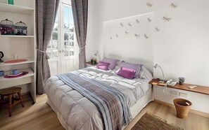 A bedroom with a bed, bedside table, lamp, and a window with curtains.