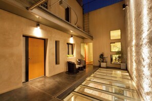 Un couloir d’hôtel avec un plancher en verre, une porte en bois et un escalier.