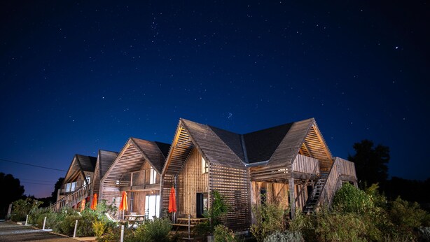 Un hotel de estilo cabaña de madera con varias habitaciones, un sendero de piedra y zonas de estar al aire libre.