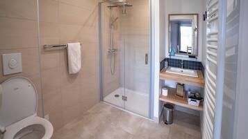 A modern bathroom with a glass-enclosed shower, a white toilet, and a vanity with a mirror and sink.