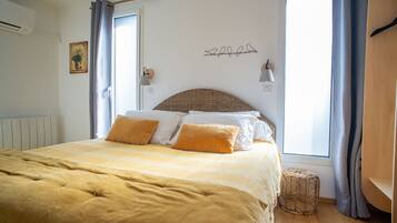 A bedroom with a large bed, a wicker headboard, and a view of the outdoors.