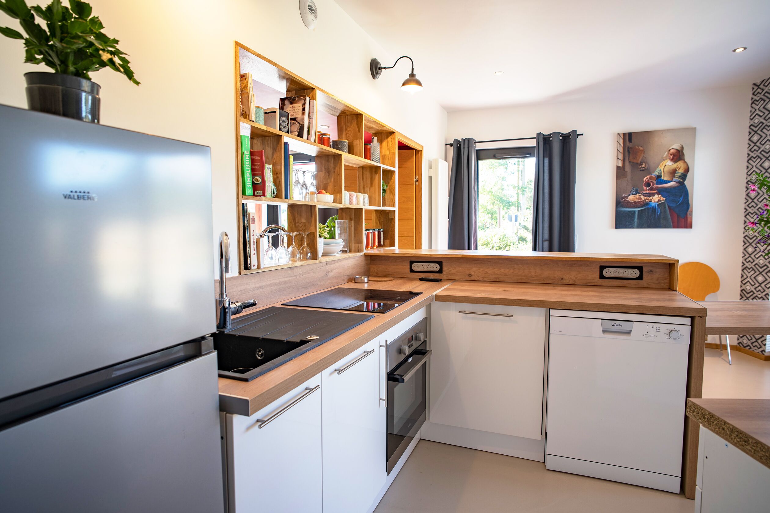 Une cuisine moderne dotée d’un lave-vaisselle encastré, d’un four et d’un plan de travail en bois.