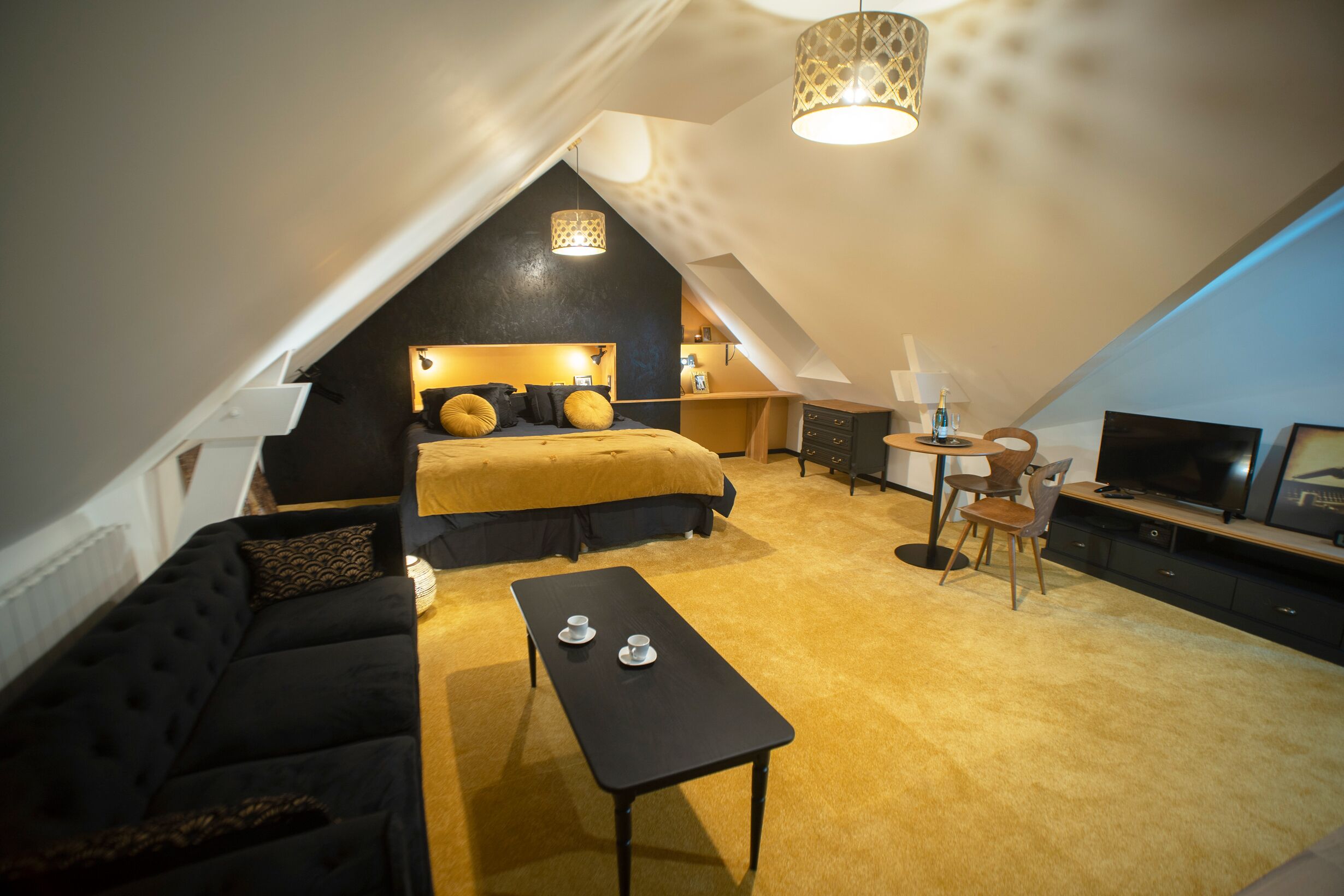 Ein gemütliches Schlafzimmer im Dachgeschoss mit Bett, Sofa, Couchtisch und Fernseher.