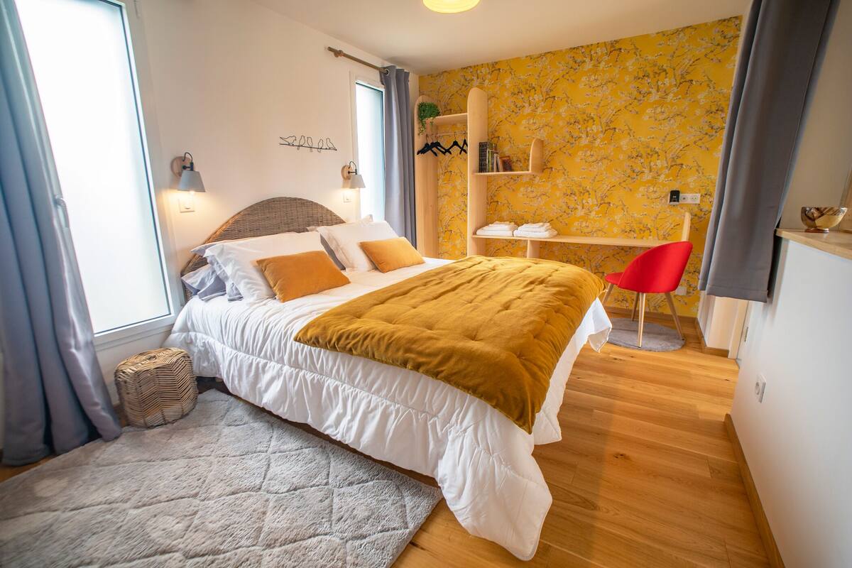 A bedroom with a bed, a desk, and a chair.