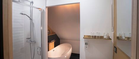 Un baño moderno con ducha de vidrio, bañera independiente y lavamanos blanco.