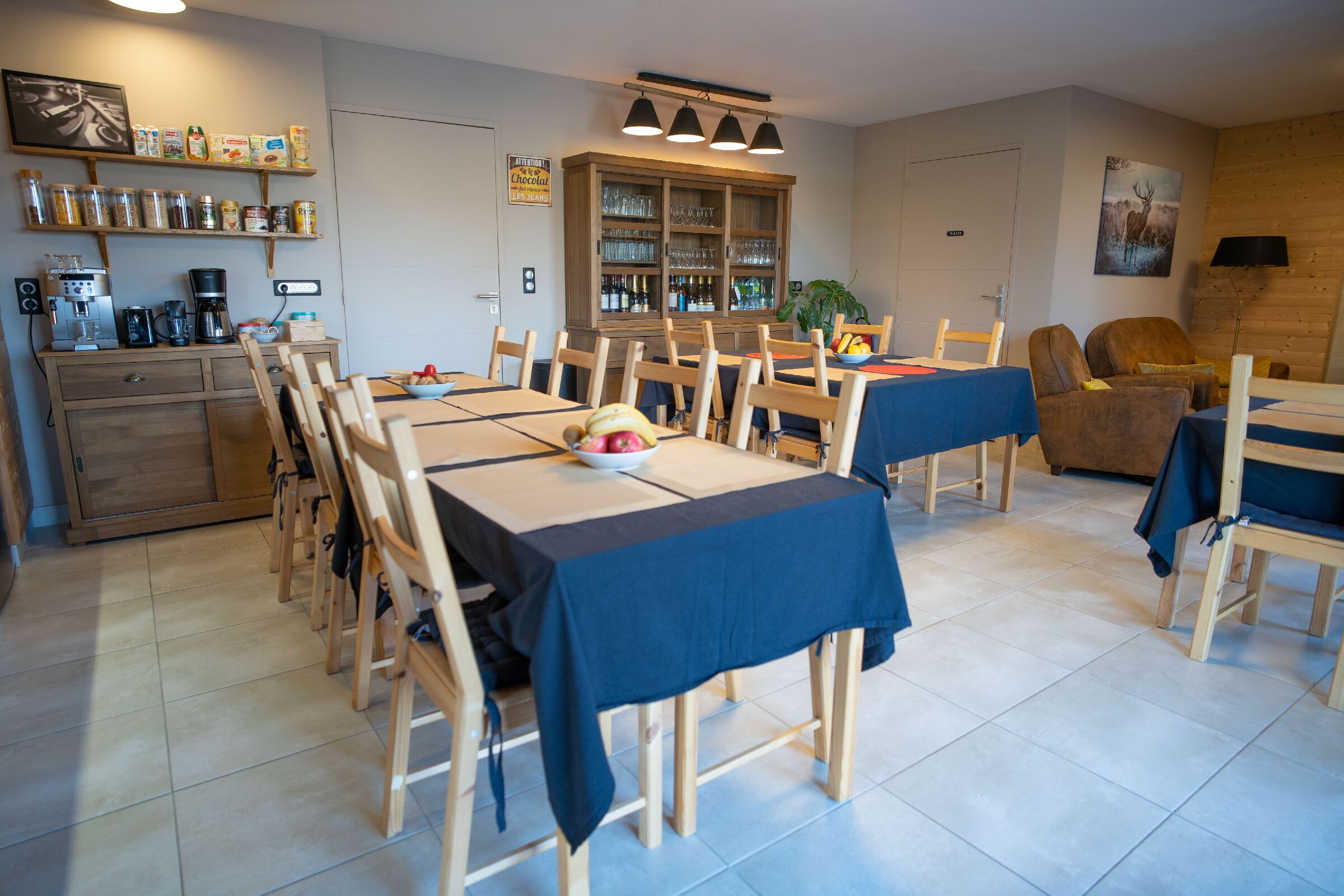 Un espace repas comprenant plusieurs tables et chaises, un coin café et un meuble contenant de la verrerie.