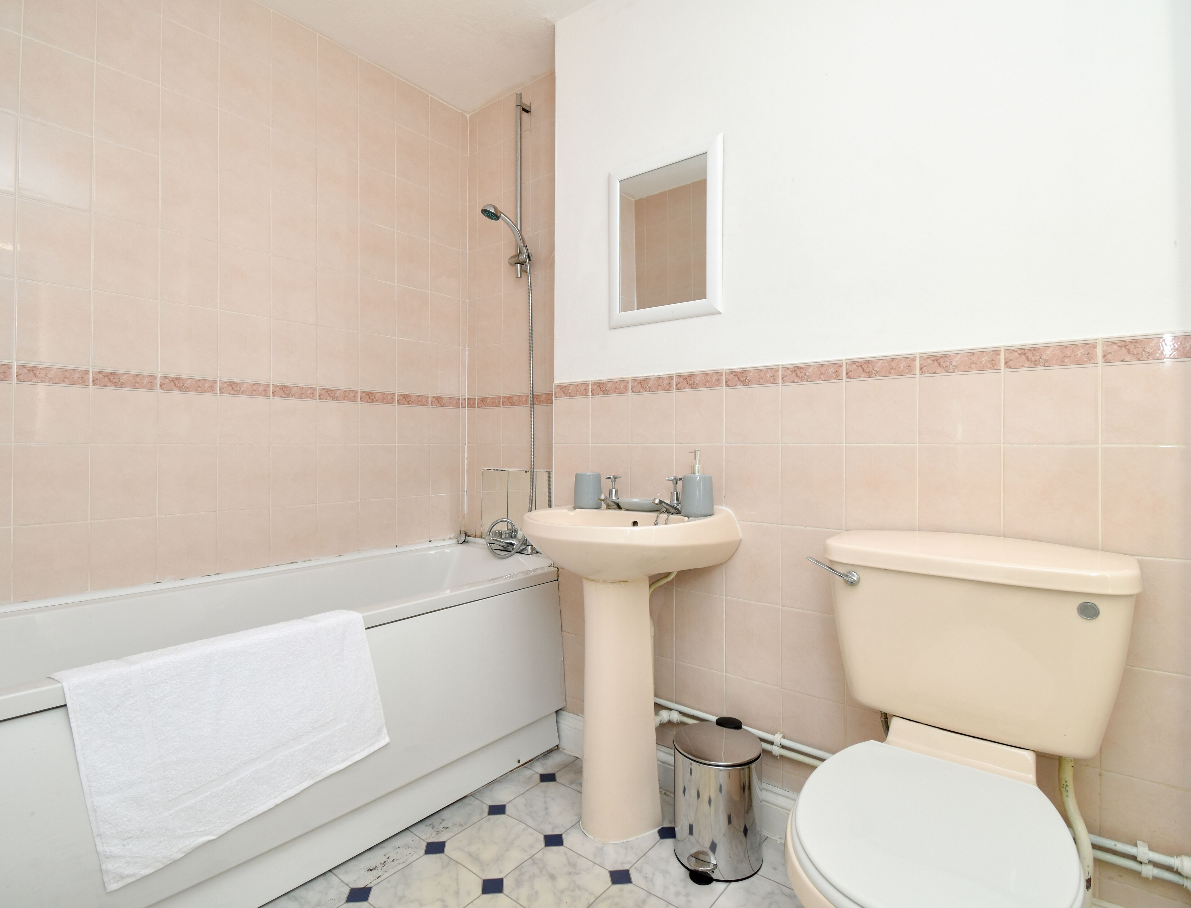 A bathroom with a bathtub, sink, toilet, and a trash can.