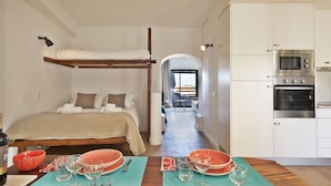A compact hotel room with a bunk bed, a kitchenette, and a dining area with a table set for two. - The Salty Lodge (Lagos)