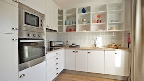 A modern kitchen with white cabinetry, stainless steel appliances, and a tiled backsplash. - The Salty Lodge (Lagos)