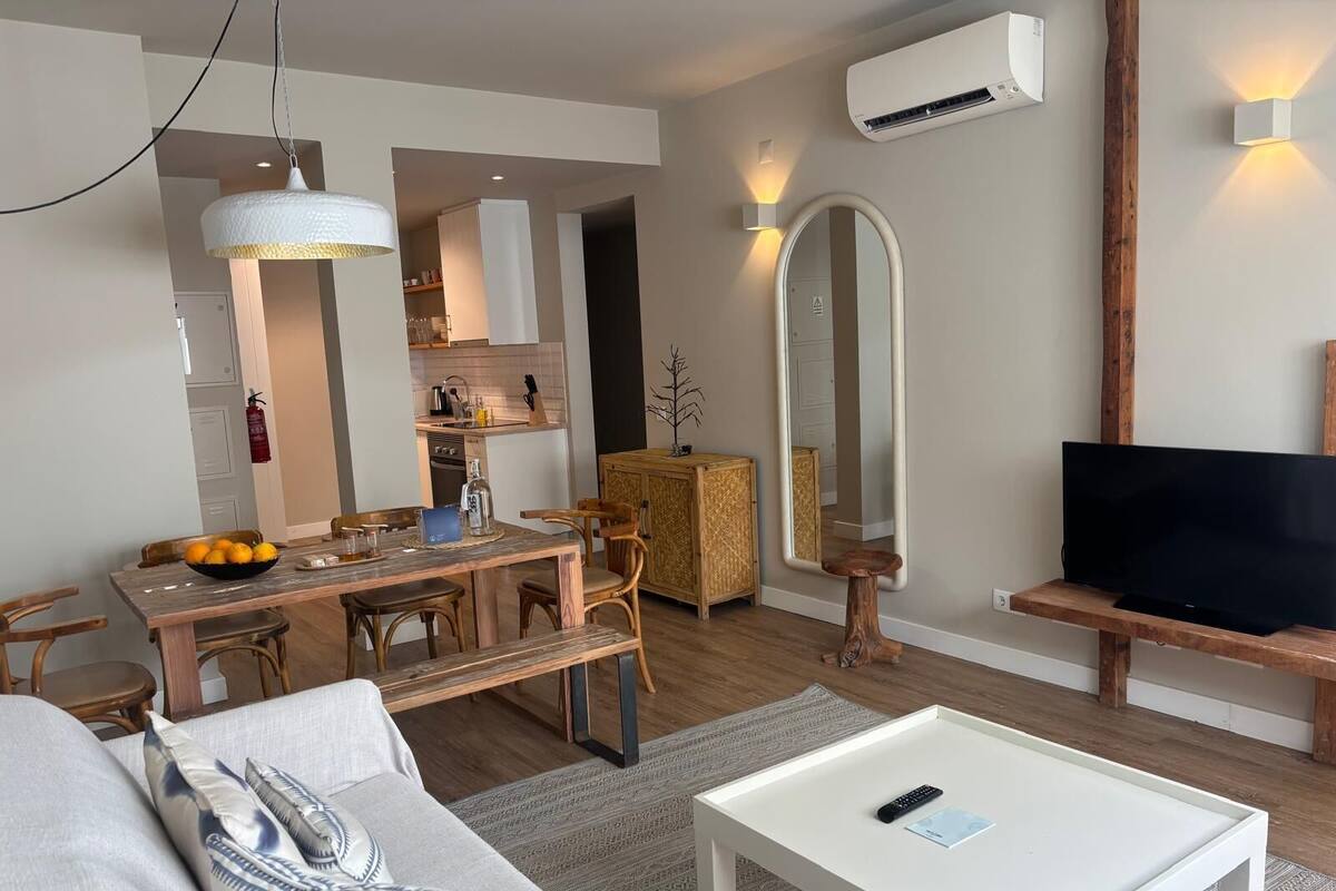 A modern living room with a dining area, a TV, and a large mirror.
