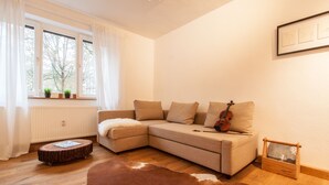 A cozy living room with a sectional sofa, a violin, a small wooden table, and a cowhide rug. - Wohnen am Ringpark (Würzburg)